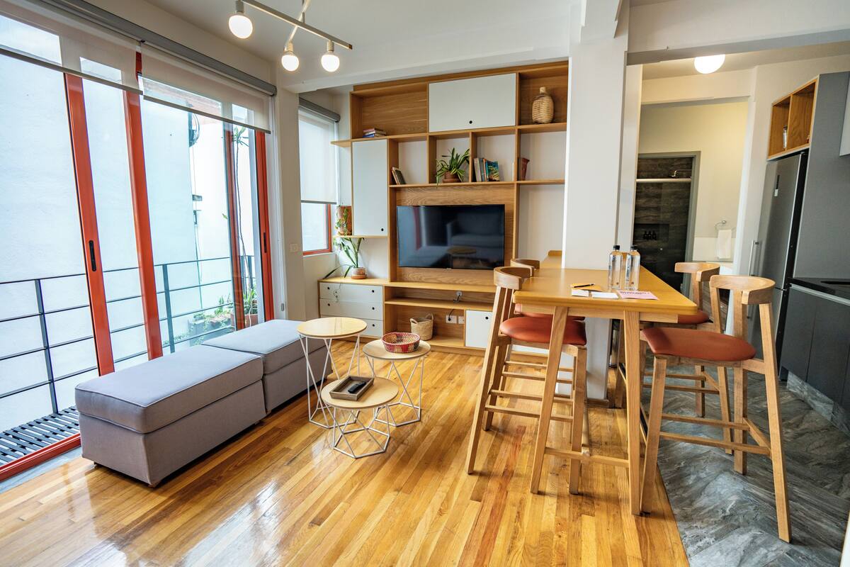Una cocina moderna con comedor, muebles de madera y un amplio ventanal que proporciona luz natural.