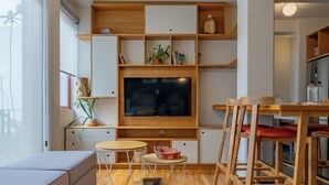 A modern living room with a TV, wooden furniture, and a dining area.