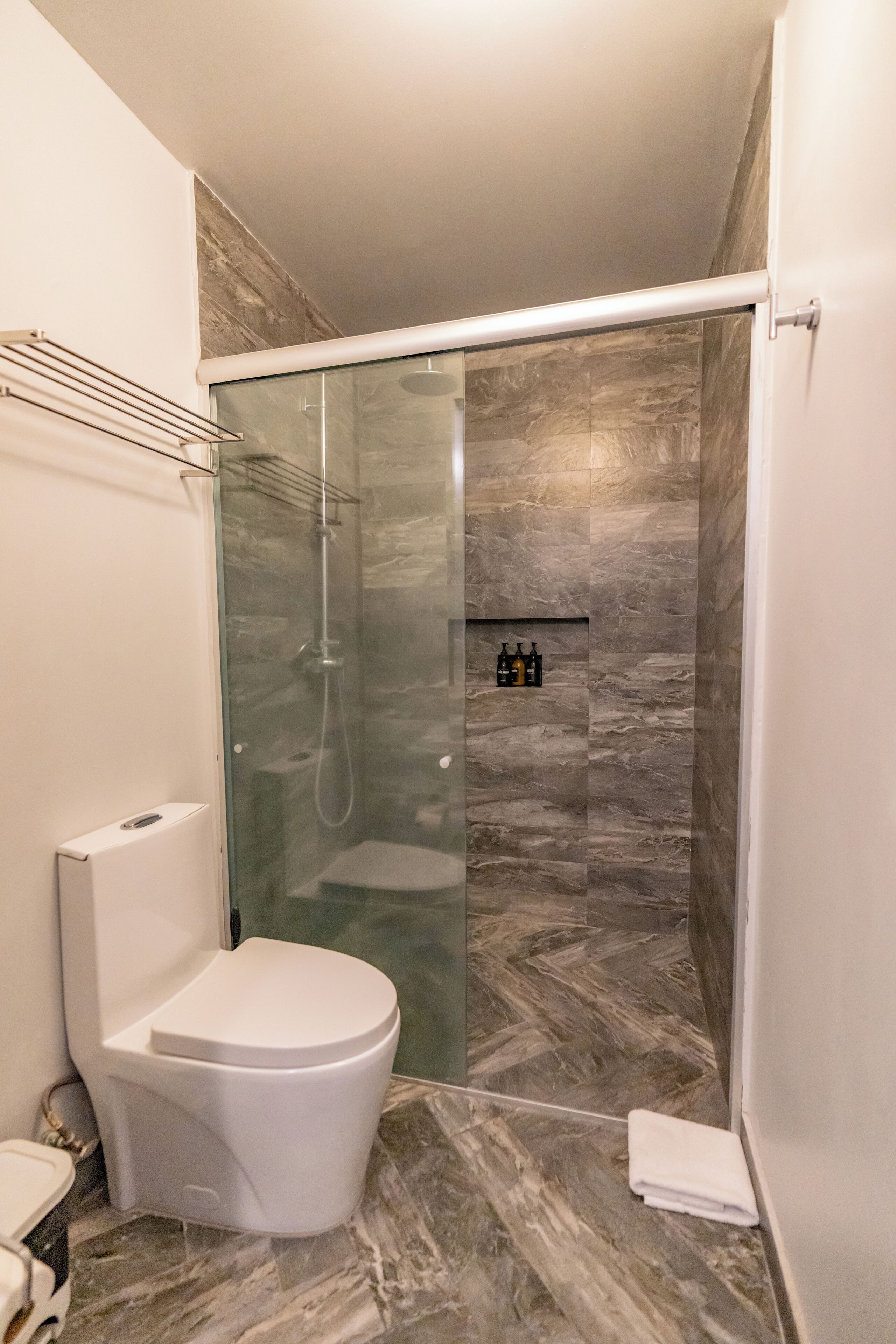 Ein modernes Badezimmer mit einer gläsernen Duschkabine, einer weißen Toilette und einem Marmorboden.