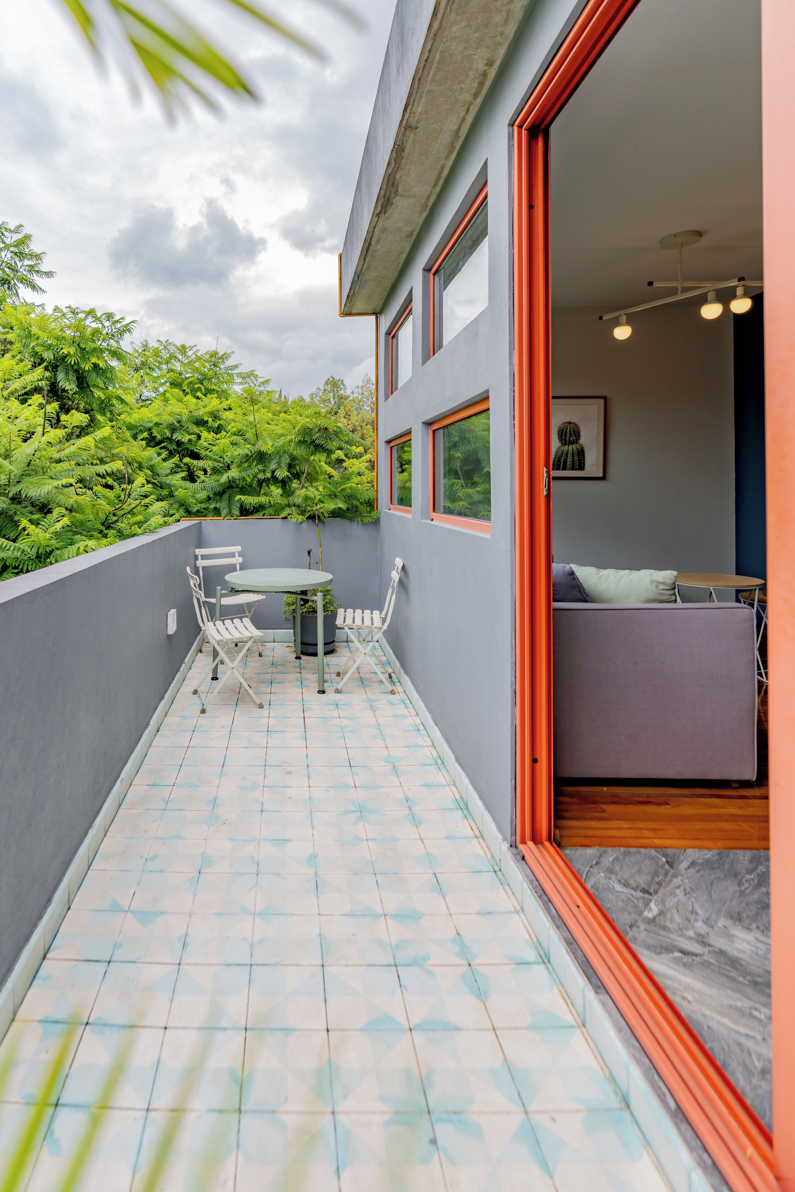 Een balkon met een tafel en stoelen, een bank en uitzicht op groen.