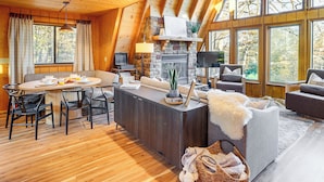 A cozy cabin interior with a dining area, sofa, and fireplace.