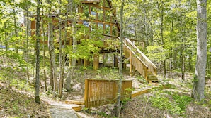 A wooden cabin with multiple levels, surrounded by dense forest.