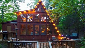 A cabin with a deck, outdoor seating, and a hot tub.
