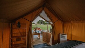 Una habitación con carpa, un escritorio de madera, una silla y una mesita con una planta.