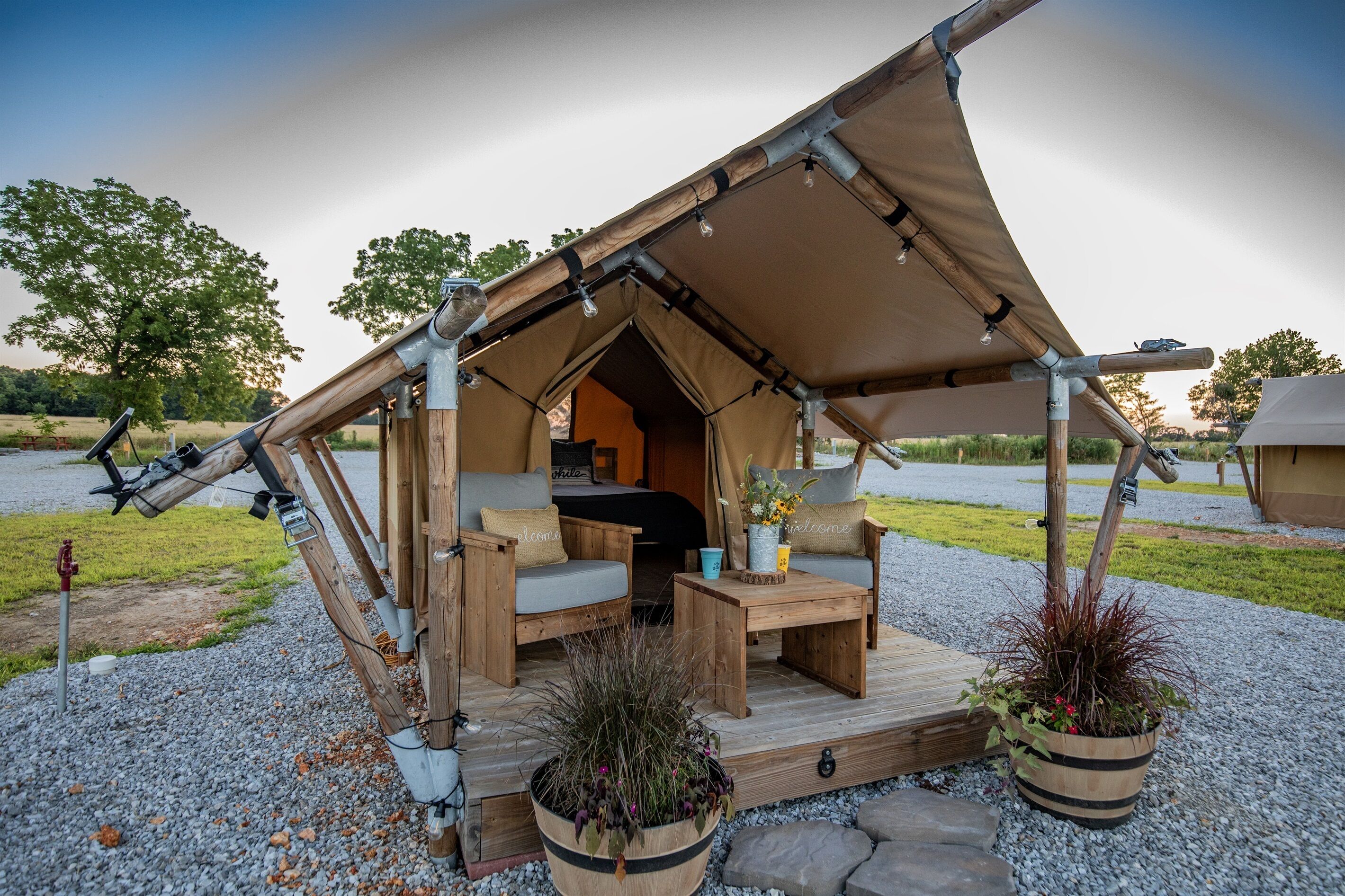A tent with a wooden interior, a sofa, a coffee table, and potted plants.