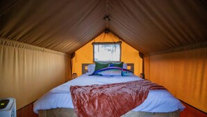 Ein Zeltraum mit einem Bett, Kissen und einer Decke.