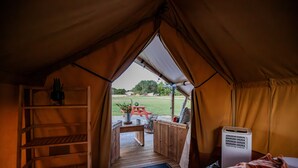 Eine Zelteinrichtung mit Holzterrasse, Fußmatte und Tisch mit Stühlen.