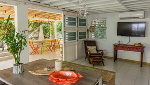 Un salon moderne avec une table à manger en bois, une plante en pot et un téléviseur fixé au mur.