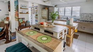 Une cuisine dotée d’un îlot central en bois, d’un coin repas avec un banc, et d’un plan de travail avec un évier et une cuisinière.