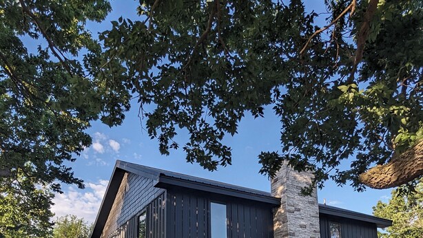 A two-story house with a stone chimney, wooden porch, and outdoor seating area. - New 5- Star Large, Private House, With No Neighbors  (Salina)