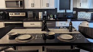 A modern kitchen with white cabinets, a black countertop, and a central island with seating. - New 5- Star Large, Private House, With No Neighbors  (Salina)