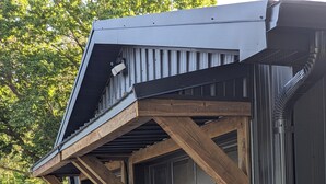 A garage with a dark door and a sloped roof supported by wooden beams. - New 5- Star Large, Private House, With No Neighbors  (Salina)
