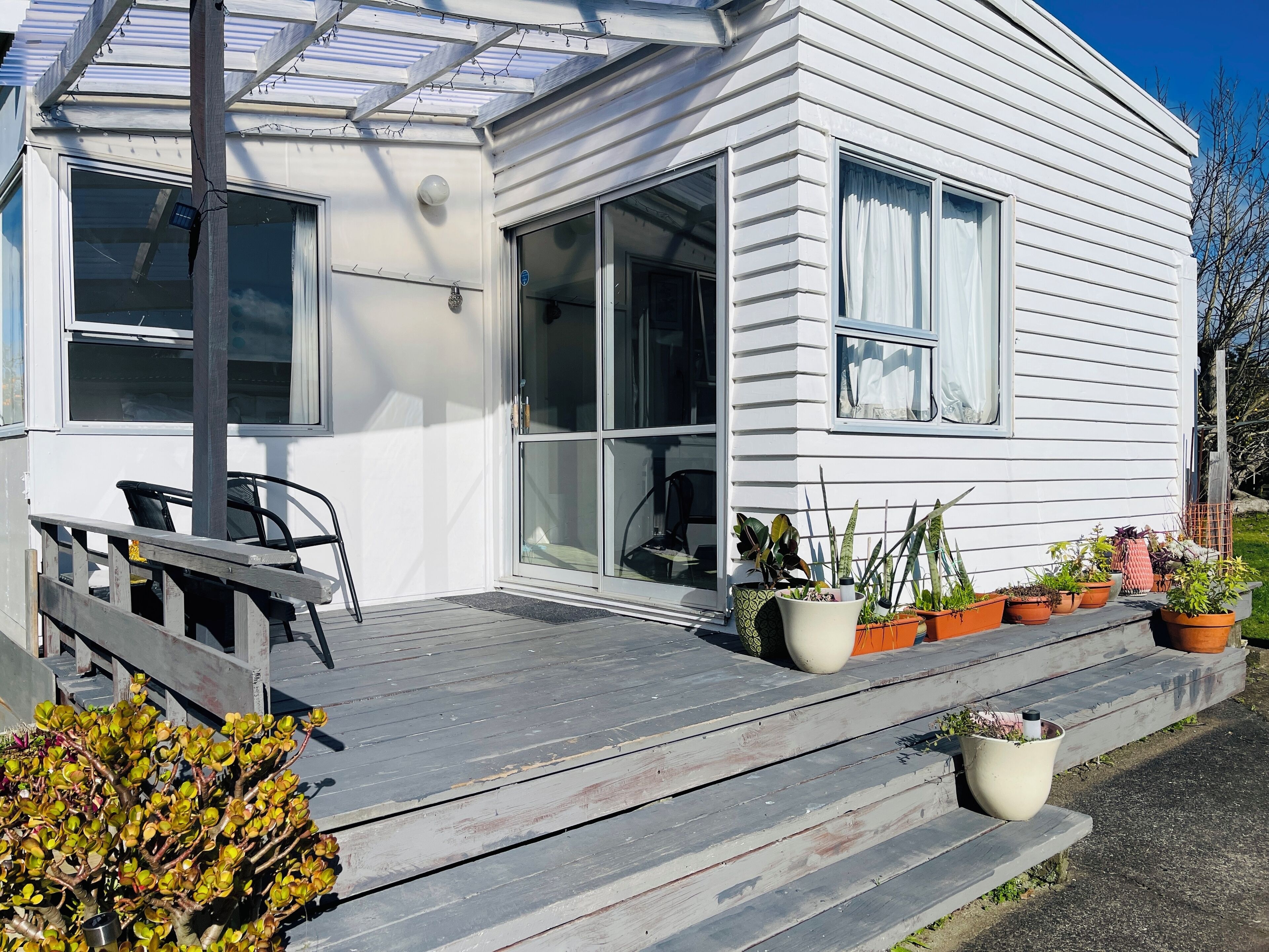 A white house with a covered porch, large windows, and potted plants.