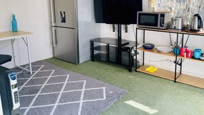 A compact kitchenette with a refrigerator, microwave, and a small table with a TV. - Haven to Relax (Hamilton)