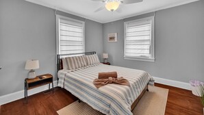 A bedroom with a bed, two bedside tables, a ceiling fan, and two windows with blinds. - Cozy 3/1 centrally located in the city.  Perfect for families. Pet friendly! (Charlotte)