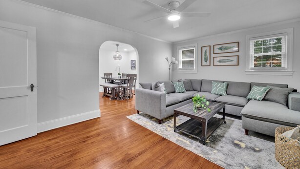A living room with a gray sectional sofa, a coffee table, and a dining area with a wooden table and chairs. - Cozy 3/1 centrally located in the city.  Perfect for families. Pet friendly! (Charlotte)
