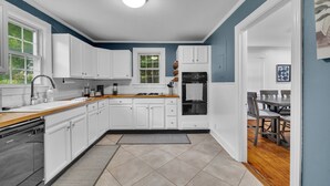 A modern kitchen with white cabinets, a wooden countertop, and a built-in oven. - Cozy 3/1 centrally located in the city.  Perfect for families. Pet friendly! (Charlotte)