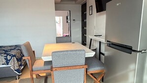 Une cuisine moderne équipée d’une table à manger, de chaises, d’un réfrigérateur et d’un téléviseur fixé au mur.