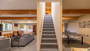 Eine Treppe führt zu einem Schlafzimmer auf dem Dachboden, ein Wohnzimmer mit einer Couch, einem Tischtennisschrank und einem Kicker.