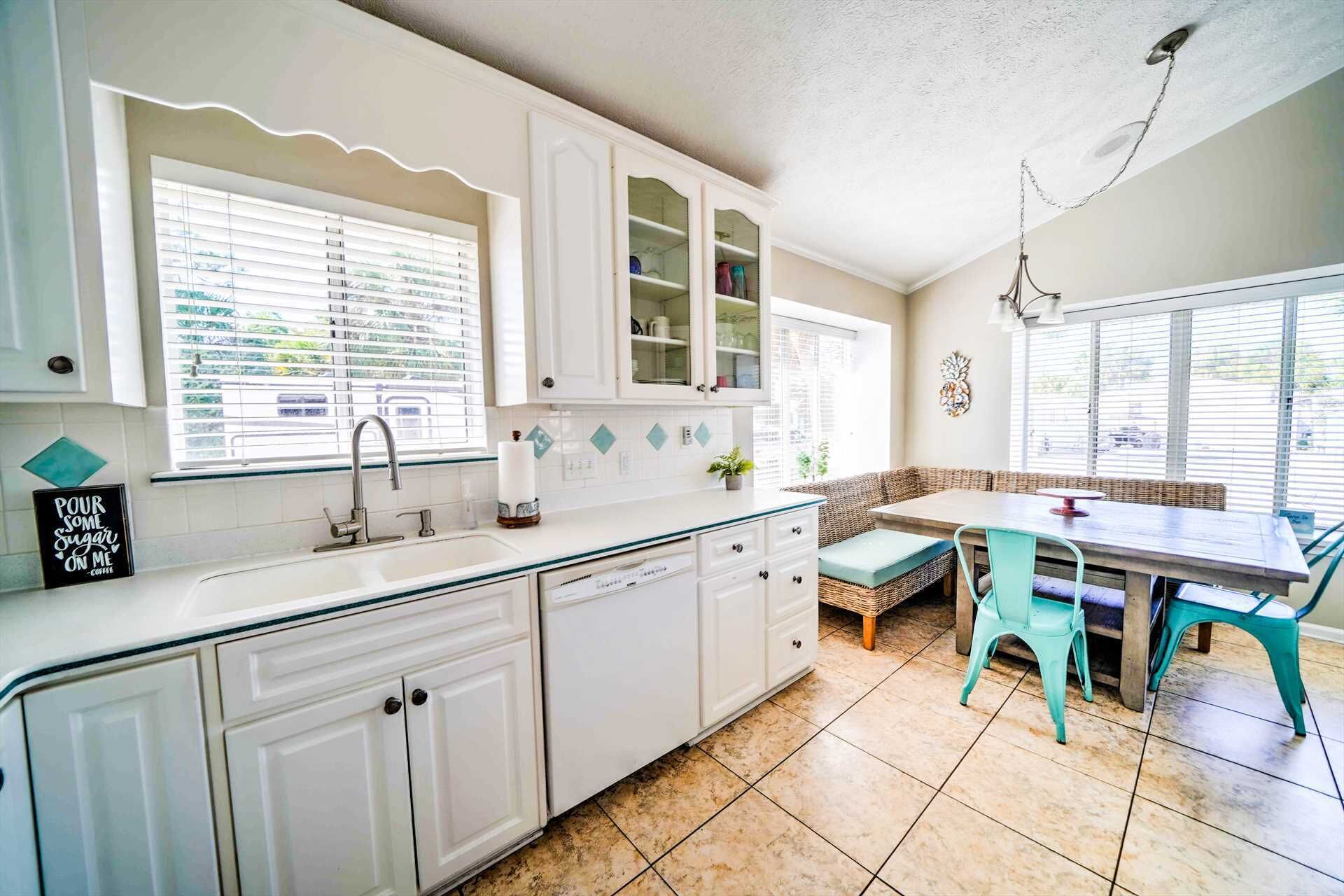 A kitchen with white cabinets, a sink, and a dining area with a table and chairs.