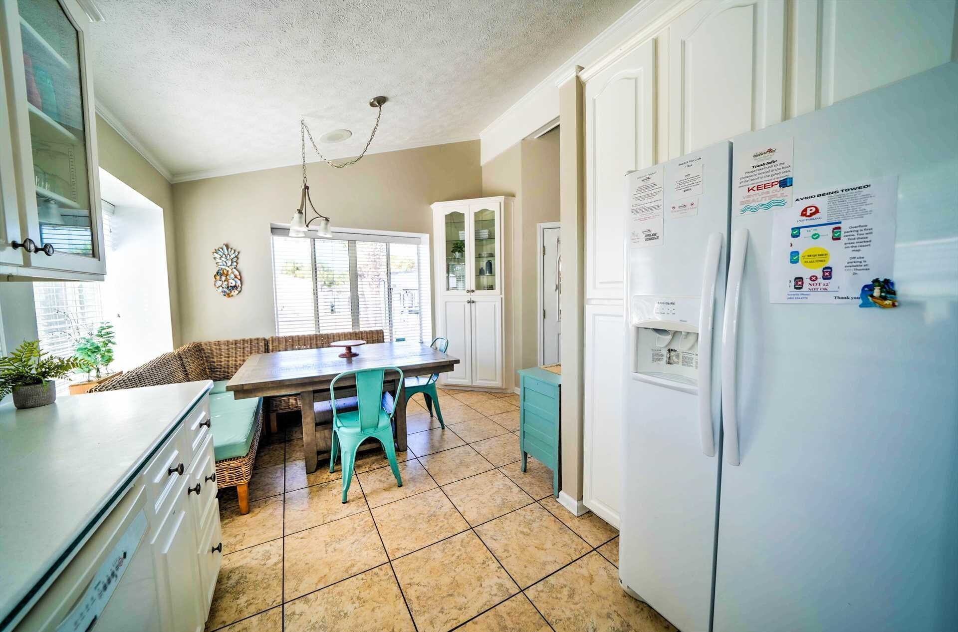 A kitchen with a dining table, chairs, a refrigerator, cabinets, and a window with blinds.