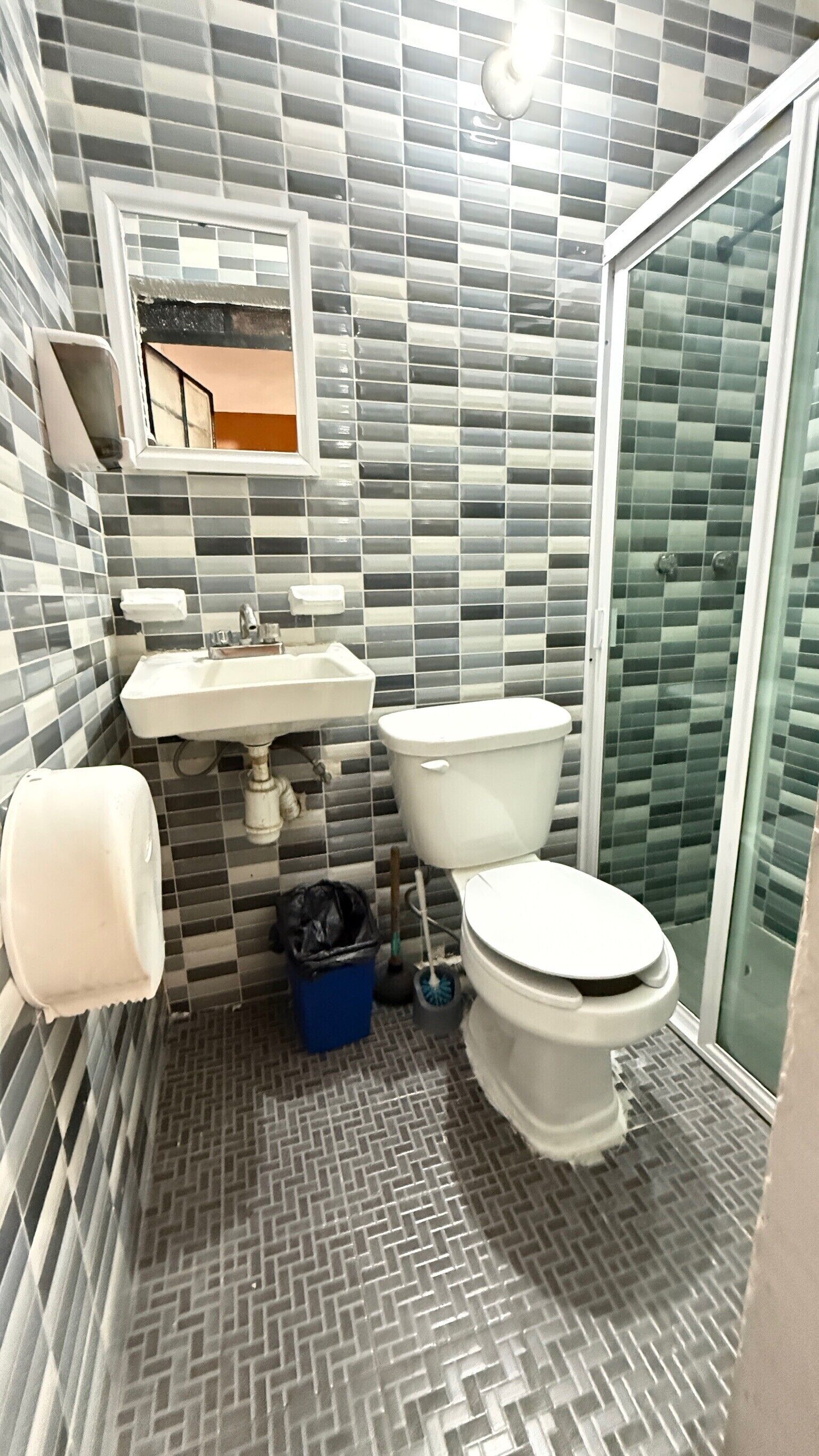 A bathroom with a tiled floor, a sink, a toilet, and a shower area.
