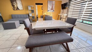 A modern living room with a marble table, grey sofas, and a large window with blinds. - Departamento Orange 2 Guadalajara (Guadalajara)