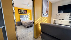 A bedroom with a bed, a sofa, a desk, and a TV. - Departamento Orange 2 Guadalajara (Guadalajara)