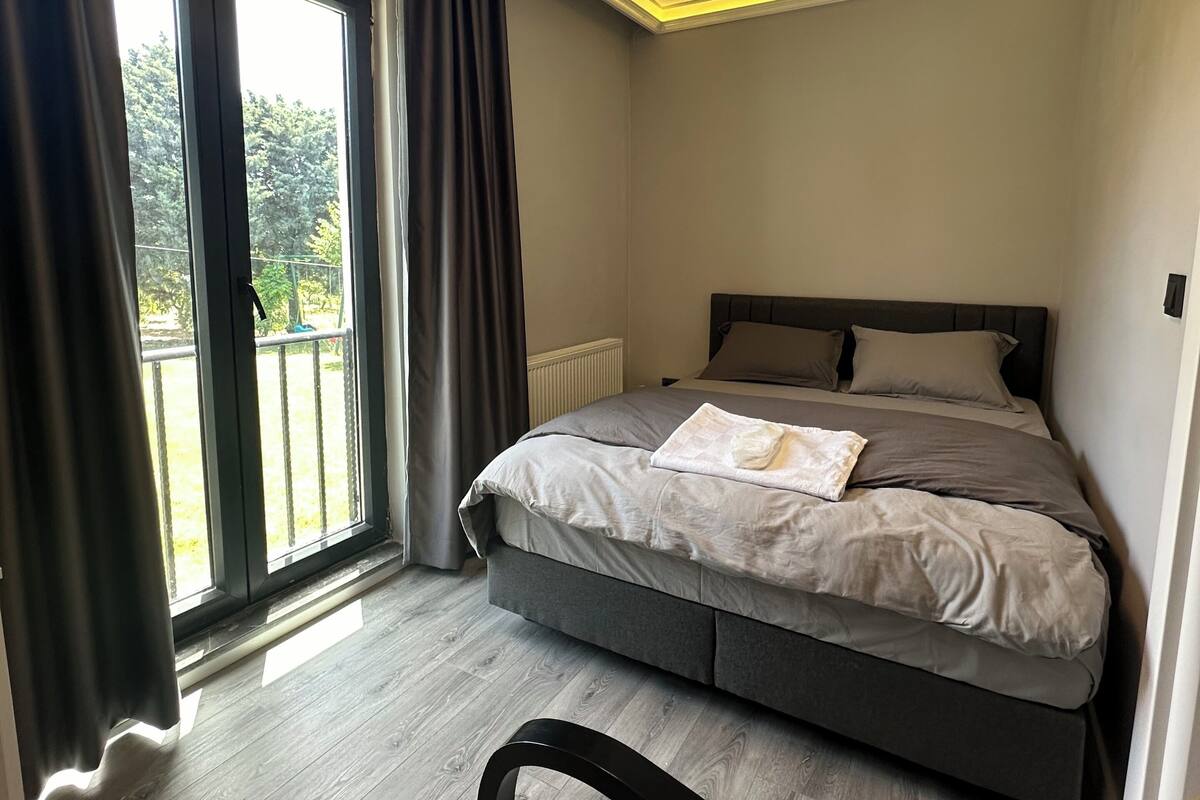 Un dormitorio moderno con una cama, vistas al exterior y una lámpara en el techo.