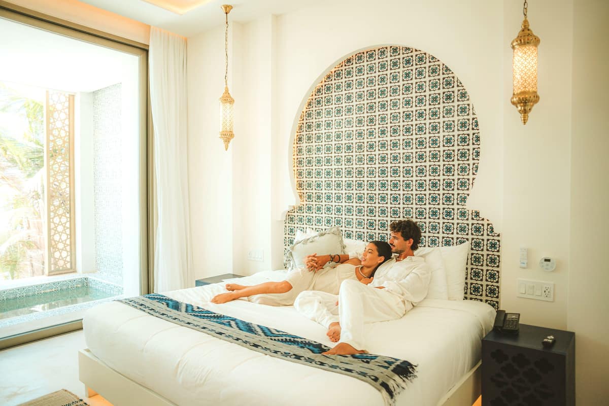Un dormitorio con una cama grande, un cabecero estampado y una mesita de noche con un teléfono.