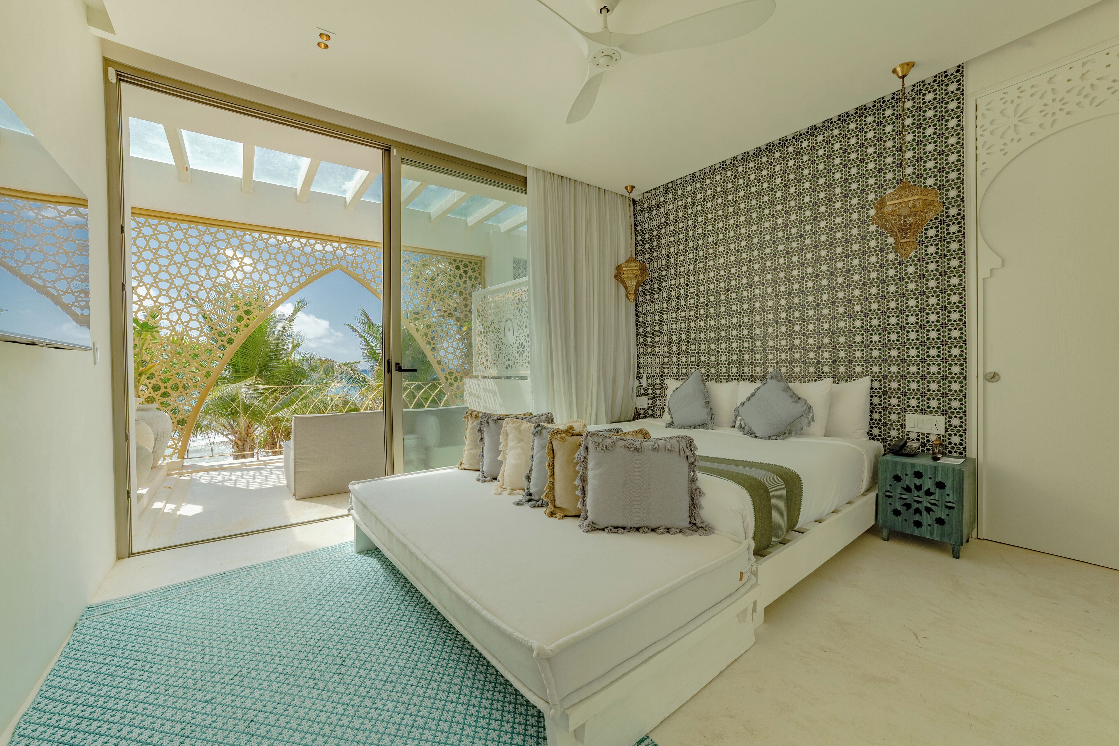 A bedroom with a large bed, a nightstand, and a view of the outdoors through a sliding glass door.