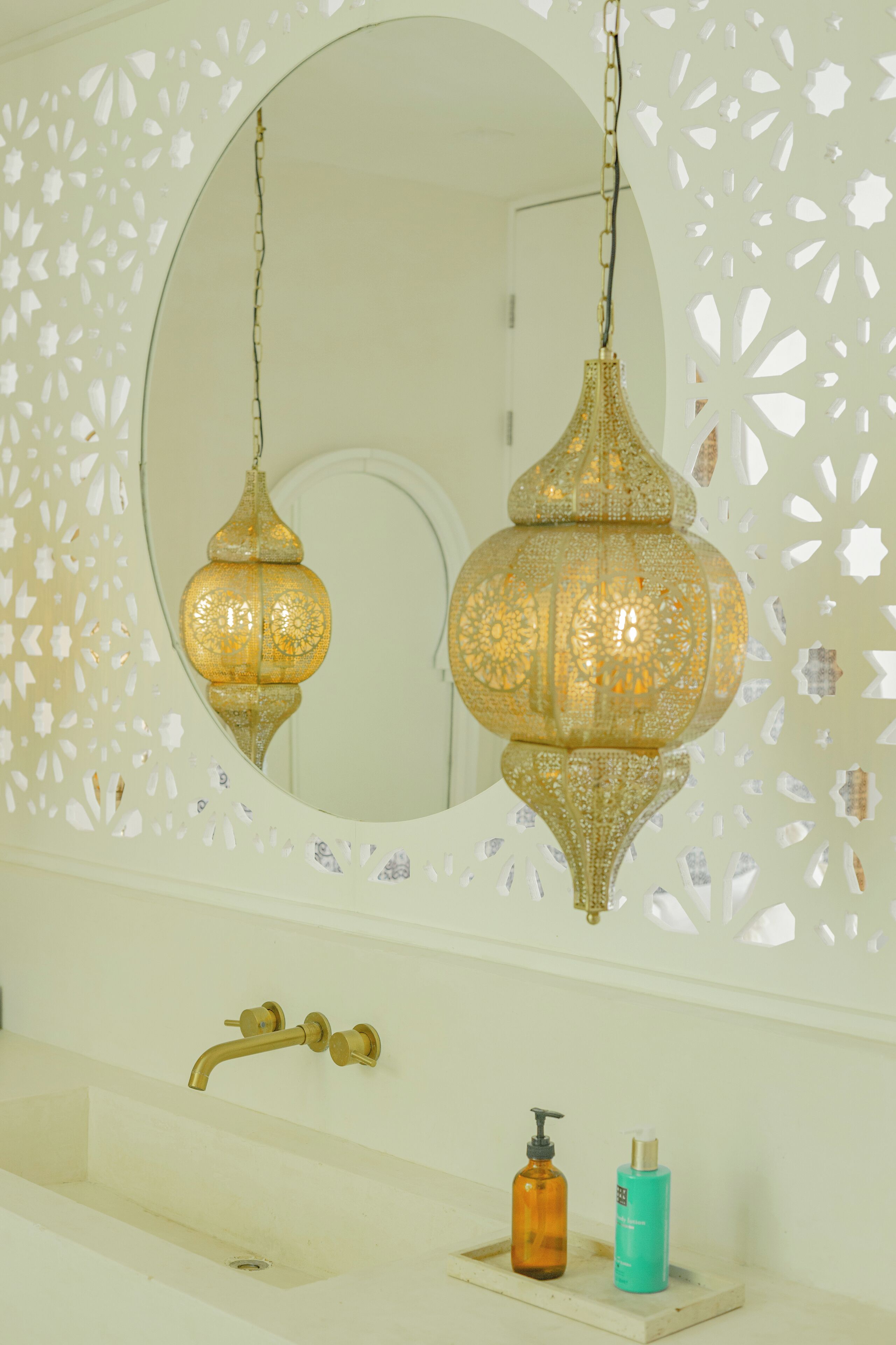 A bathroom with a white sink, gold faucet, and two bottles on the counter.