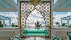 A view through a decorative archway with a pool and outdoor seating area. - Sana Tulum Beachfront Boutique Hotel (Tulum)