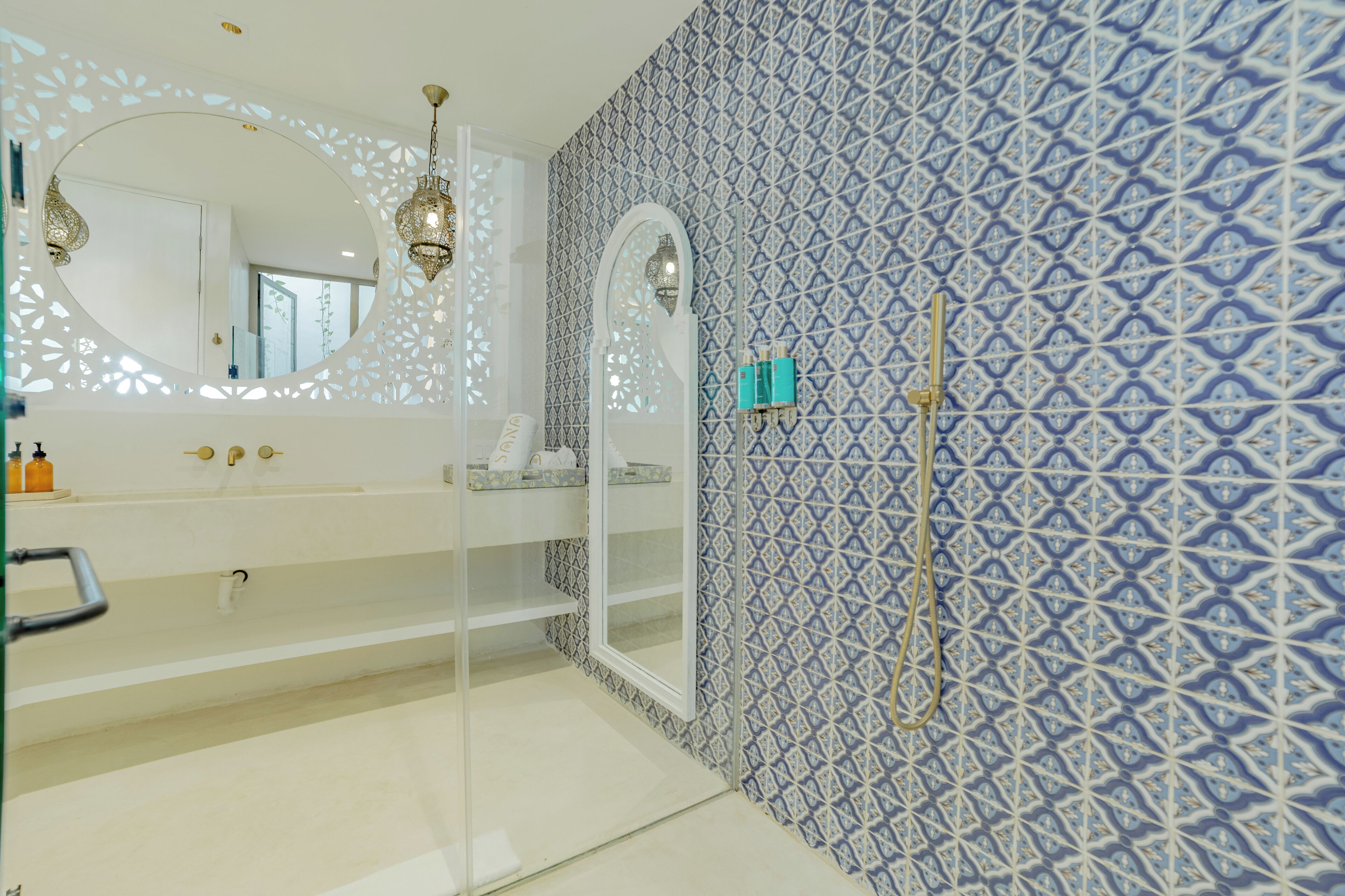 A bathroom with a white sink, a large mirror, and a patterned wall.