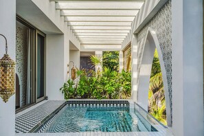 A pool area with a tiled floor, surrounded by greenery and decorative elements. - Sana Tulum Beachfront Boutique Hotel (Tulum)