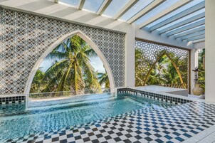 A pool area with a checkered floor, decorative wall tiles, and a view of palm trees.