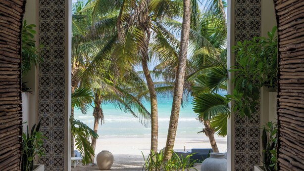 A beach view through an arched doorway with patterned walls and potted plants. - Sana Tulum Beachfront Boutique Hotel (Tulum)