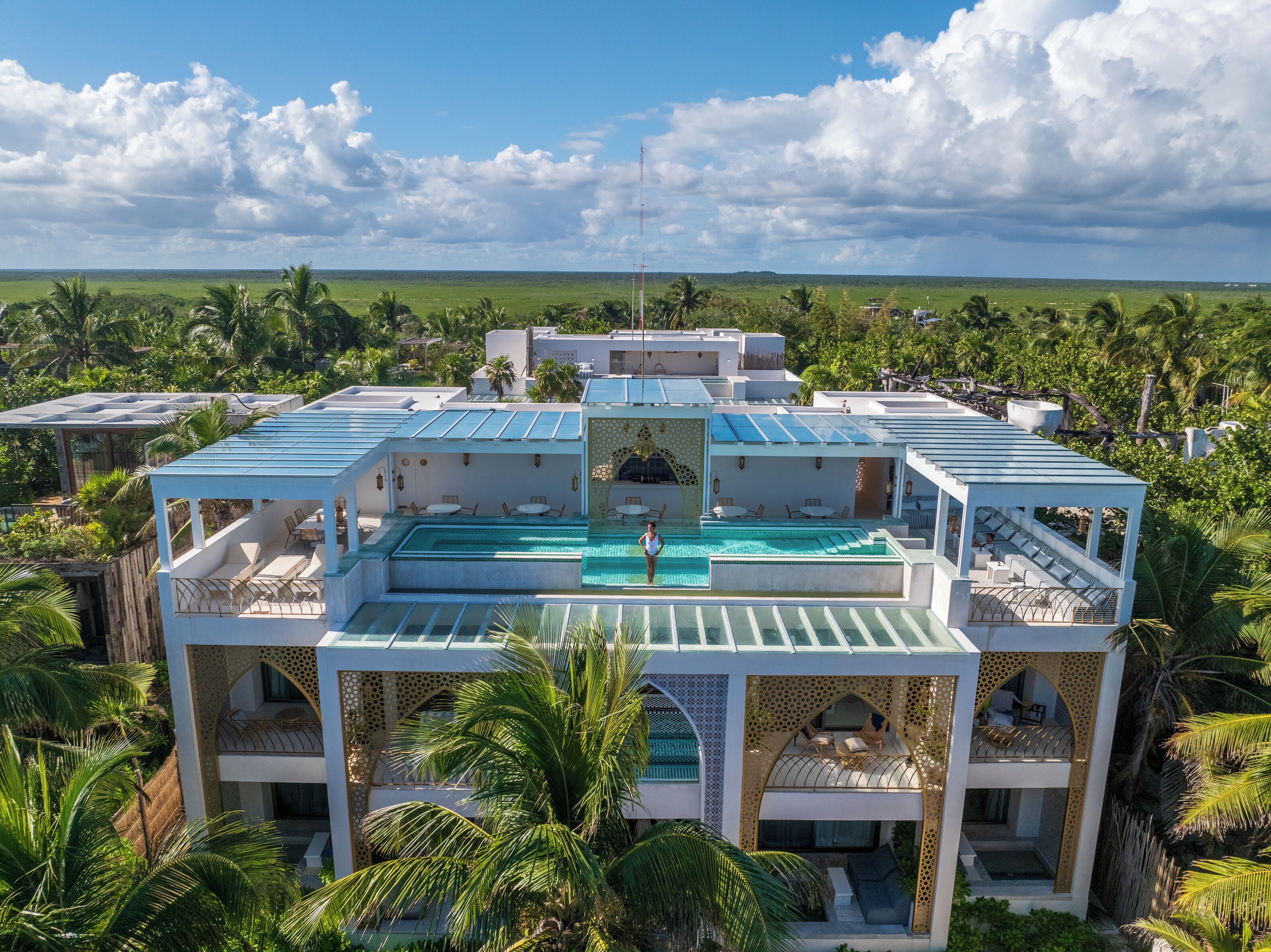 A resort with multiple swimming pools, a large central pool, and a view of the surrounding landscape.