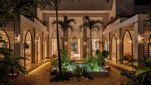 A luxurious outdoor area with a pool, palm trees, and a covered seating area. - Sana Tulum Beachfront Boutique Hotel (Tulum)