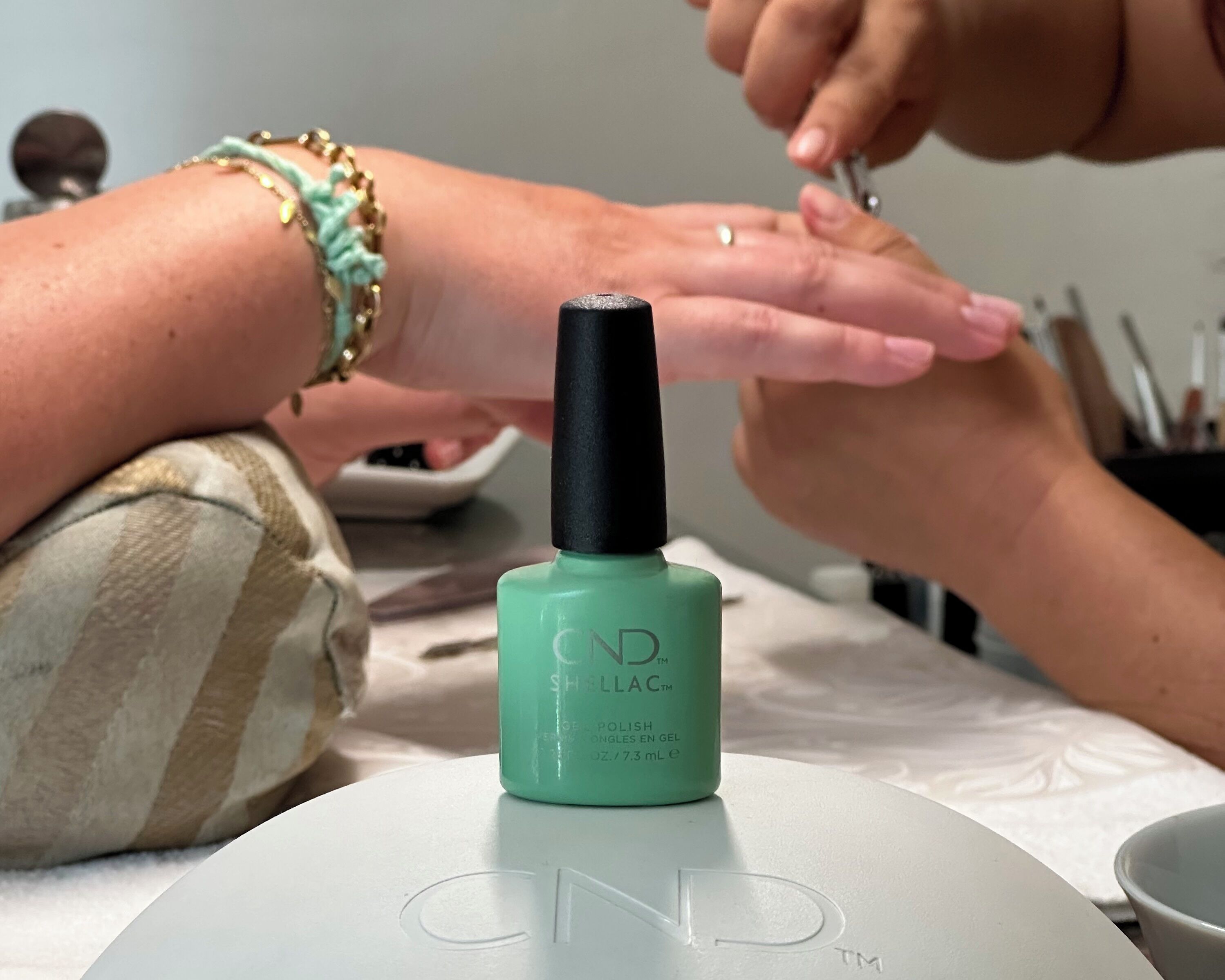 A nail polish bottle on a table with a logo that reads "CND".