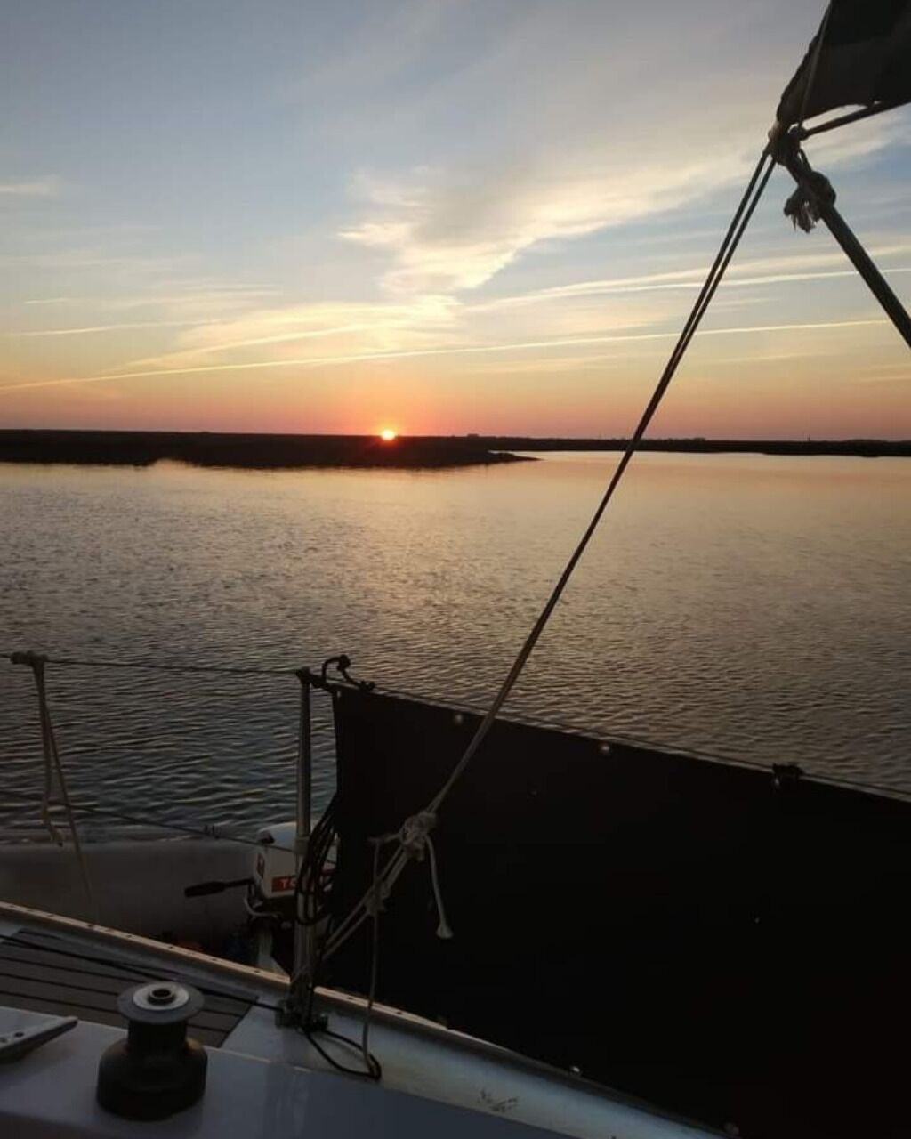 Un cuerpo de agua tranquilo al atardecer con un bote en primer plano.