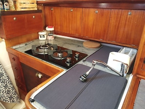 A compact kitchenette with a gas stove, a sink with a faucet, and cabinets above.