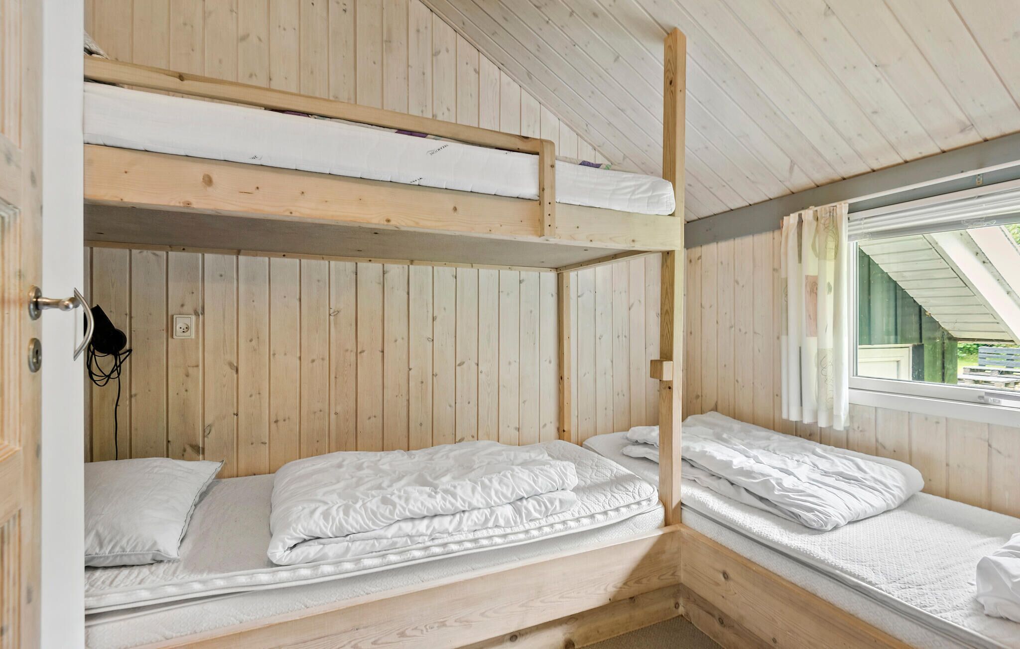 A bunk bed room with wooden walls and a window.