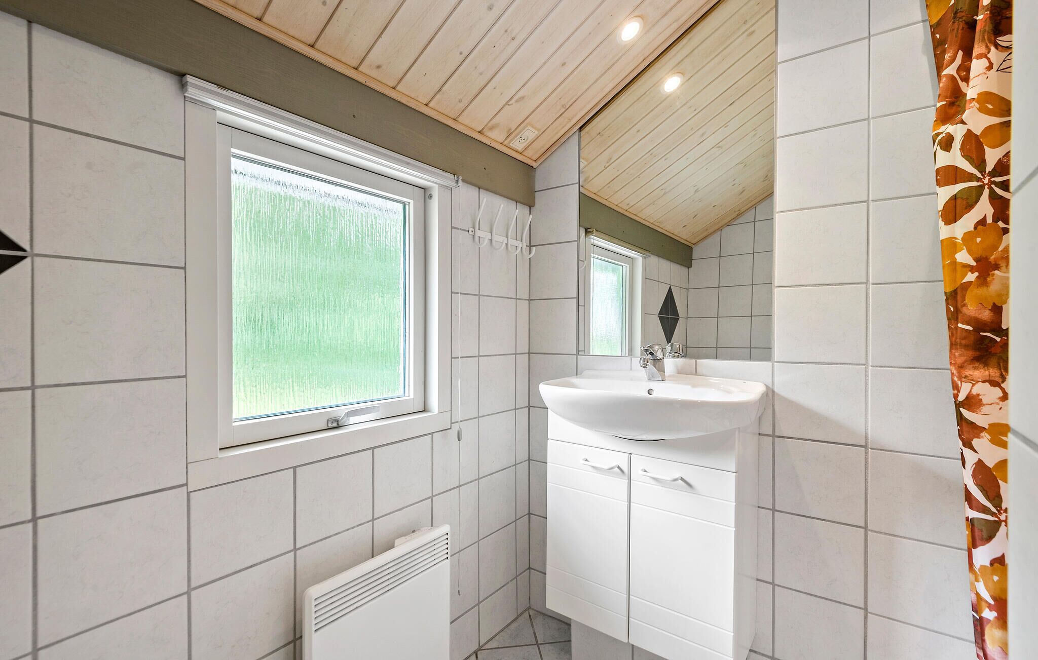 A bathroom with a window, a sink, and a radiator.