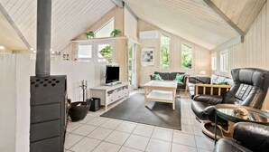 Ein großzügiger Wohnbereich mit Kamin, Fernseher, einer Couch und einem Esstisch.
