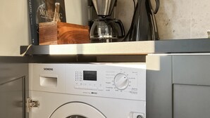 A Siemens washing machine with a digital display and control panel, located in a kitchen area with a coffee maker and a book on the counter.