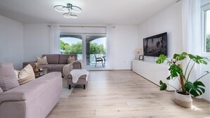 A spacious living room with a sofa, a coffee table, and a potted plant. - Beautiful home in Pula (Pula)
