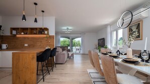 A modern kitchen with a wooden island, black bar stools, and a dining area with a white table set for six. - Beautiful home in Pula (Pula)