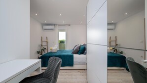 A modern bedroom with a bed, a desk, and a chair. There is a window with a view of greenery outside. - Beautiful home in Pula (Pula)