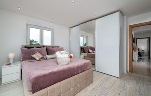 Relax in this serene bedroom with a large bed, plush footboard, and elegant nightstand.